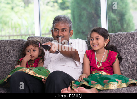 indian father watching tv with his daughter on living room Stock Photo