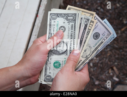 A person holding and counting dollar notes. Stock Photo