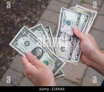 A person holding and counting dollar notes. Stock Photo