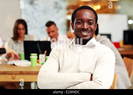 Portrait of a cheerful businessman sitting in front of colleagues Stock Photo