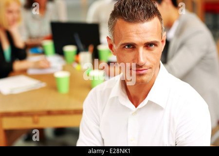 Portrait of happy businessman sitting in front of colleagues Stock Photo