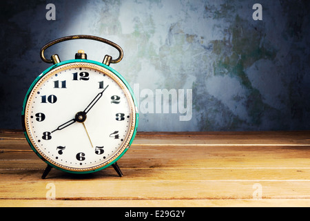 Retro alarm clock on wooden table on grunge background Stock Photo