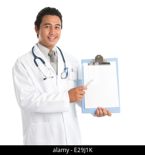 Portrait of southeast Asian male medical doctor showing and pointing to a blank empty clip file with space , standing isolated on white background. Young man model. Stock Photo