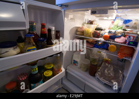 Door to a Refrigerator open with light on showing contents Stock Photo