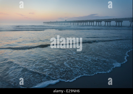 The colors of dawn paint the morning mist at the Jacksonville Beach Pier in Northeast Florida, USA. Stock Photo