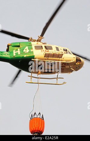Bell 412 registration EC-IPM carrying water for fire fighting, Cabopino Golf, Andalusia, Spain. Stock Photo