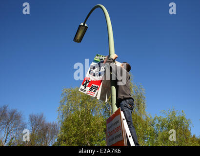 A man from Eastern Europe hanging up election posters for the radical German rightwingers party NPD (German Nationaldemocratic Paty) ahead of the European elections on April 16, 2014. Photo: Wolfram Steinberg dpa Stock Photo