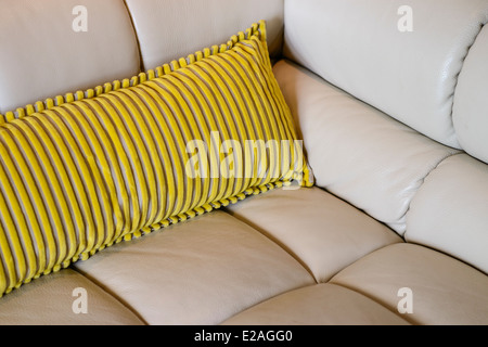 Yellow cushion on a beige leather sofa Stock Photo