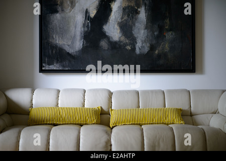 Leather sofa with yellow pillows and painting on the wall Stock Photo