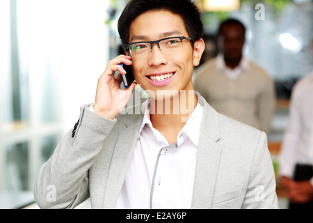 Portrait of a happy businessman talking on the smartphone in front of colleagues Stock Photo