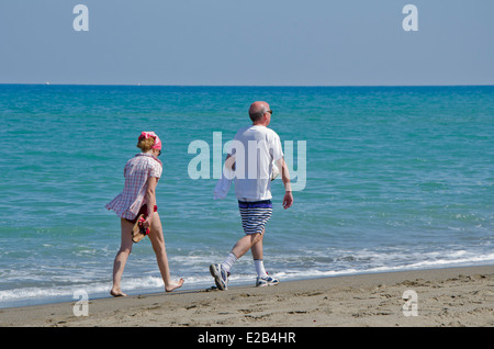 Retired couple walking on the beach at Fuengirola, Costa del Sol, Spain. Stock Photo