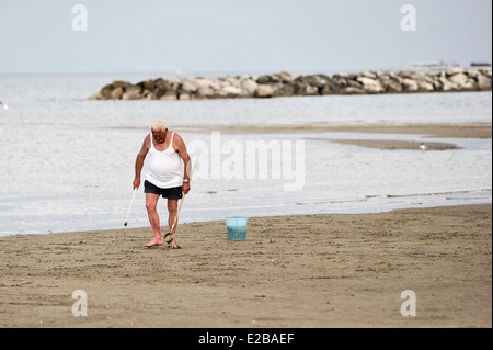 Man looking for shellfish on the beach in Rimini, Italy Stock Photo