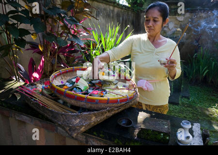 Indonesia, Bali, Tabanan, hotel Puri Taman Sari, woman burning incense and offering offerings of the morning Stock Photo