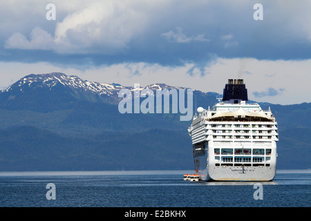 Cruise ship anchored outside Icy Strait Point Alaska snow capped mountains in the background. Stock Photo