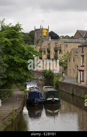 View of canal boats moored & yellow banner on church before Le Tour de France - Springs Branch, Leeds-Liverpool Canal, Skipton, Yorkshire, England. Stock Photo