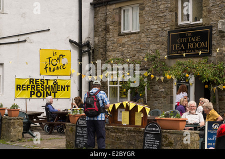 People enjoying refreshments, sitting, eating & drinking alfresco in the sun - outside The Cottage Tearoom, Kettlewell, North Yorkshire, England, UK. Stock Photo
