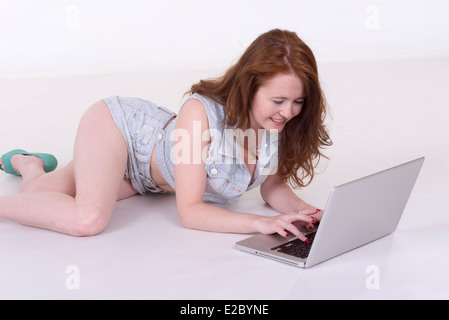 Woman using laptop computer laying on the floor Stock Photo