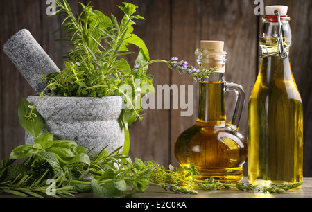 herbs and oil on wooden table Stock Photo