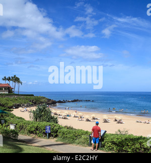 Man reads sign along coastal walkway in front of Wailea Beach on Maui Stock Photo