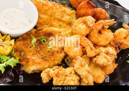 Fried seafood platter with fish, shrimp, oysters, hush puppies, and a crab cake. Stock Photo