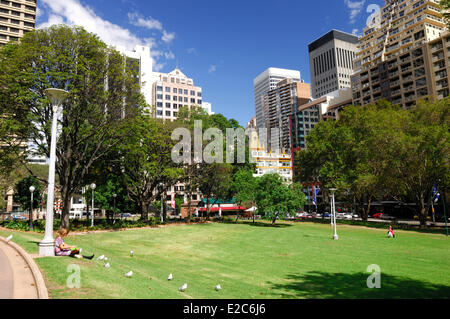 Australia, New South Wales, Sydney, Hyde Park South, woman lunching sitting on the grass and leaning against a lamppost Stock Photo