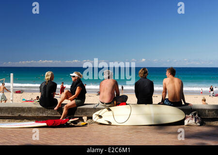 Australia, New South Wales, Sydney, Manly, tourists from behind sitting on a small wall and looking at the sea
