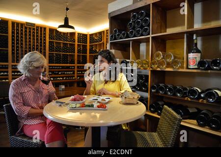 France, Herault, Beziers, square Jean Jaures, wine bar and tapas Le chameau Ivre, young womens tasting a glass of wine in a storeroom which acts of restoring Stock Photo