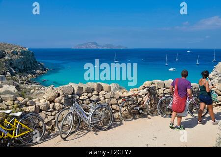 Italy, Sicily, Egadi islands, island of Favignana, Cala Rossa, walkers on a path lined with stone wall with a panoramic view on Stock Photo