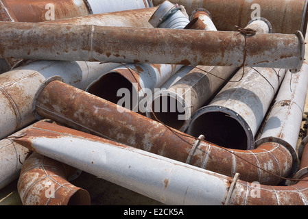 A stack of rusty and damaged industrial pipes and other metal products. Stock Photo