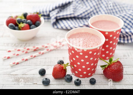 Milk shake with fresh berries and straws on wooden background Stock Photo