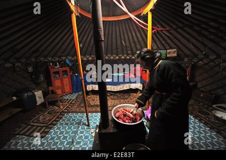 Mongolia, Tov province, Baganuur, elevated view of father and mother with daughter, preparing meat in yurt Stock Photo