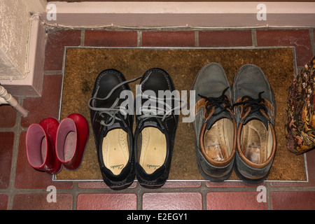 Shoes and small wellingtons on door mat studio Stock Photo