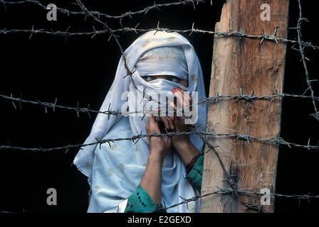 Pakistan Khyber Pakhtunkhwa Kalash valleys Bumburet valley veiled girl behind barbed wire balcony of her house Kalash converted to Islam through love or necessity about ten Kalash given up their cultural identity so per year and can no longer participate Stock Photo