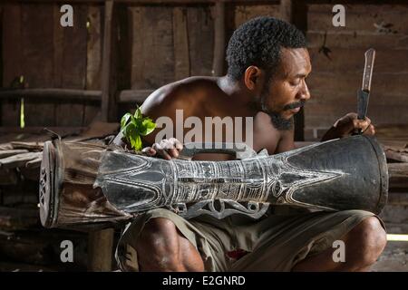 Papua New Guinea New Britain island West New Britain province Cap Gloucester district Kimbe area Rilmen village man cleaning a kundu a traditionnal drum Stock Photo