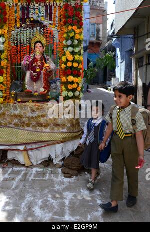 India Uttar Pradesh State Mathura a young boy and his little sisters come back at home after school passing by a temple before Holi festival celebrations Stock Photo