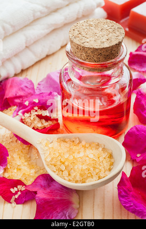 essential oil in glass bottle, sea salt, towel and rose petals Stock Photo