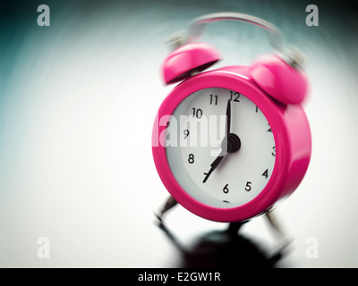 pink Alarm clock ringing on bedside table Stock Photo