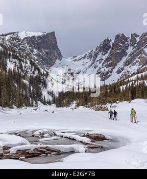 United States Colorado Rocky Mountains Rocky Mountain National Park snowshoers over frozen Dream Lake Hallett Peak on Continental Divide in background Stock Photo