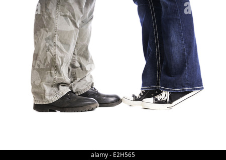 Feet and lower legs of a man and a woman as they kiss with her up on her toes. Stock Photo