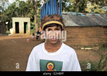 Sao Paulo, Brazil. 17th June, 2014. 13-year-old boy Wera Jeguaka Mirim wears a headdress as he poses in his village Krukutu, State of Sao Paulo, Brazil, 17 June 2014. At the World Cup opening ceremony on 12 June he had a protest banner reading 'Demarcacao ja' - black letters on red ground. The slogan can be translated with 'Borderlines now', which refers to the demand of the indigenous people for more land. Photo: Sebastian Erb/dpa/Alamy Live News Stock Photo