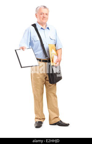 Full length portrait of a mailman holding clipboard and bunch of envelopes Stock Photo