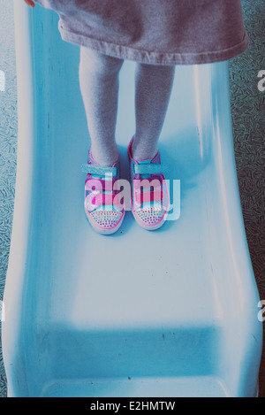 Girl standing on slide, wearing colorful sneakers, low section Stock Photo
