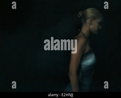Young woman walking in darkness, side view Stock Photo