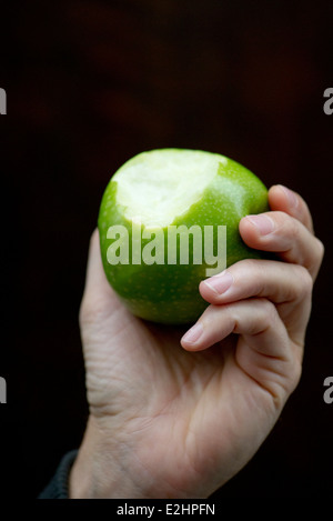 Hand holding apple with bite missing Stock Photo