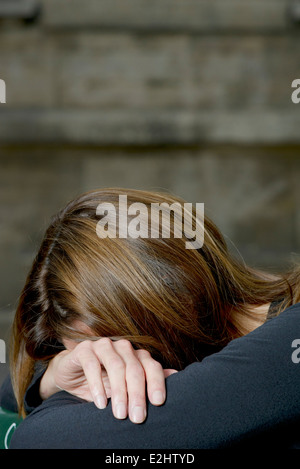 Woman resting head on arms Stock Photo