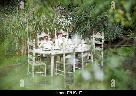 Children seated at dining table floating on lake Stock Photo