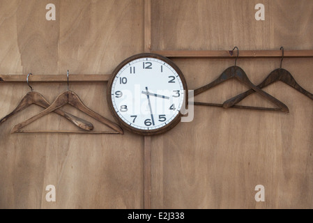 Wall clock and empty hangers on coat rack Stock Photo