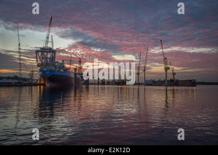 Ships under repair as the sun sets at a dry dock in Singapore Stock Photo
