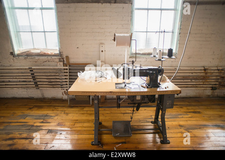 An antique, black Singer sewing machine attached to an antique table with a foot pedal sits in a corset factory in Cortland, NY. Stock Photo