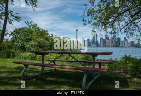 A picnic table sits on the edge of the Toronto Island Park over looking the inner harbour and the Toronto skyline. Stock Photo